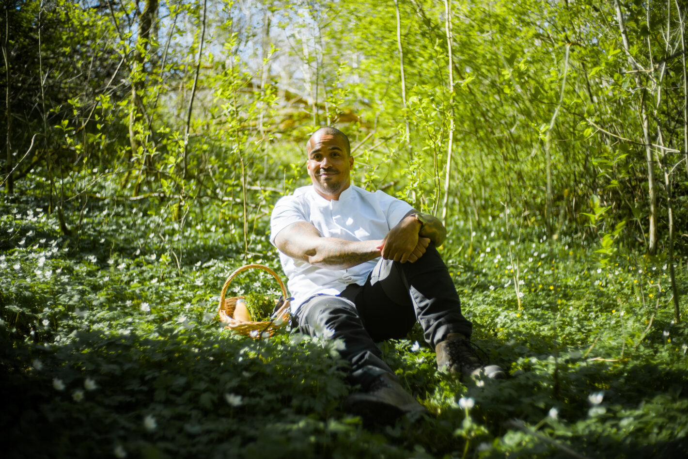 En man sitter i skogen med korg bredvid sig