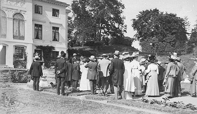 Ett svart- och vitt fotografi på en folkmassa framför Gunnebo slott i tidsenlig klädsel från 1700-talet.